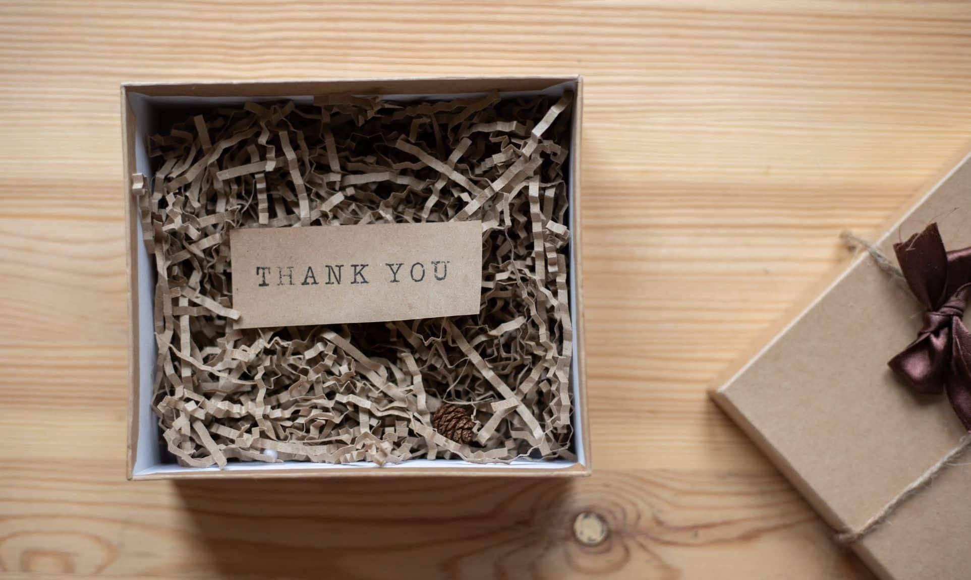 A note that says "thank you" stamped on a kraft card in a karft box