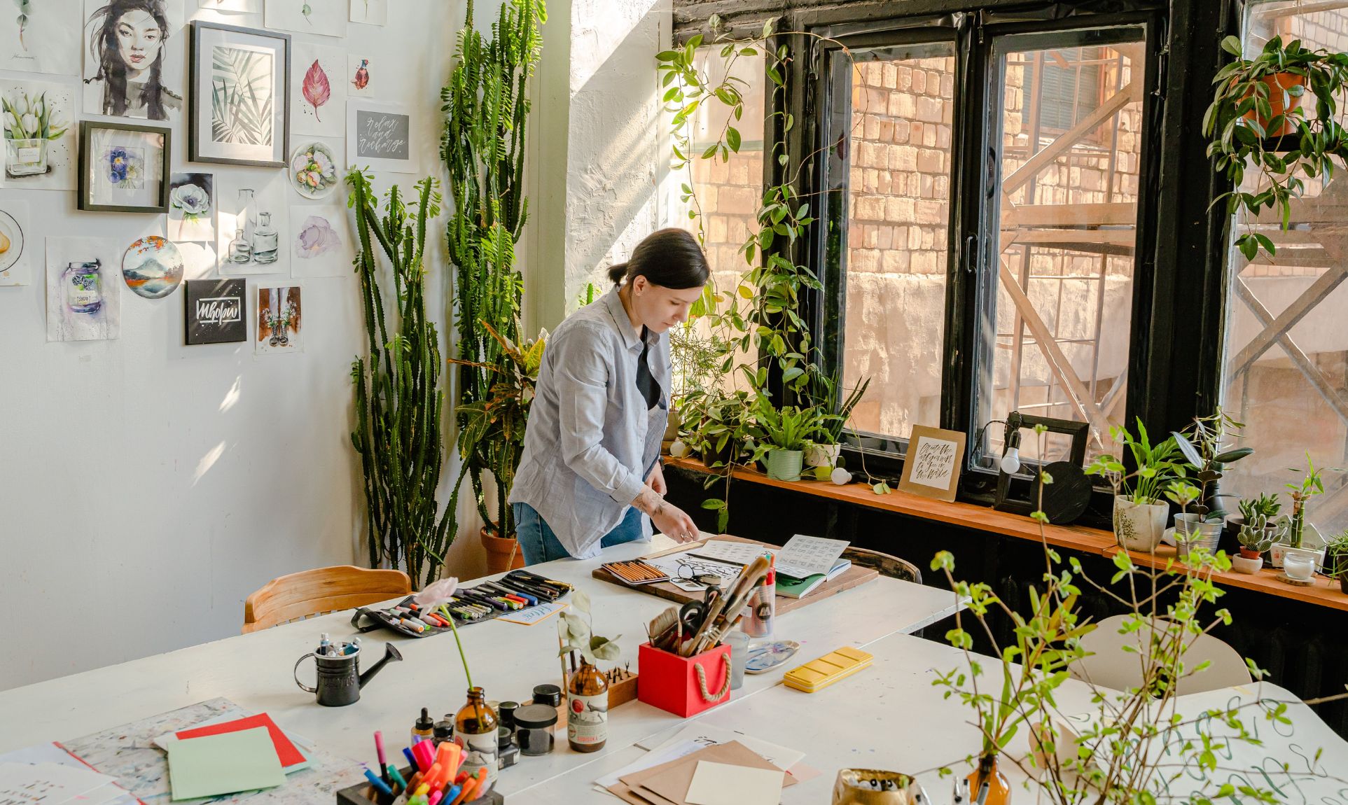Woman crafting in brightly lit workshop with plants